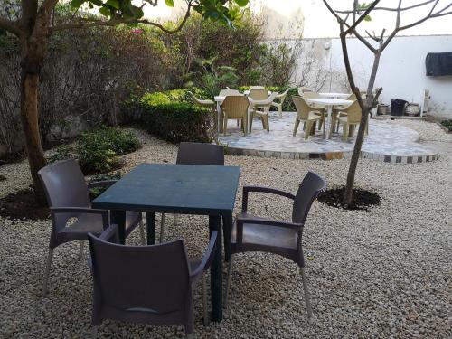 einen Tisch und Stühle in einem Garten mit Tischen und Stühlen in der Unterkunft Auberge Keur Diame in Dakar
