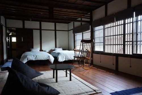 a room with two beds and a table and a chair at しぼり染めが体験できる古民家宿MADO in Arimatsu