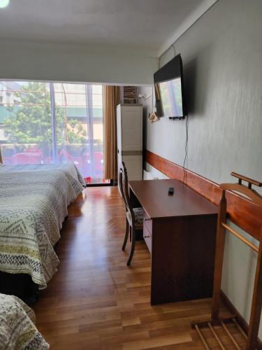 a hotel room with two beds and a desk and a television at NEW HOTEL CRUZ DEL SUR in Concepción