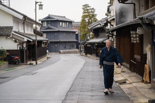 Ein älterer Mann, der eine Straße entlangläuft. in der Unterkunft しぼり染めが体験できる古民家宿MADO 