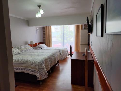 a bedroom with two beds and a window at NEW HOTEL CRUZ DEL SUR in Concepción