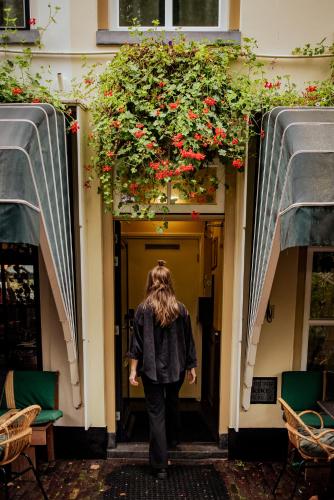 a woman walking into a building with flowers at Long John's Pub & Hotel in Amersfoort
