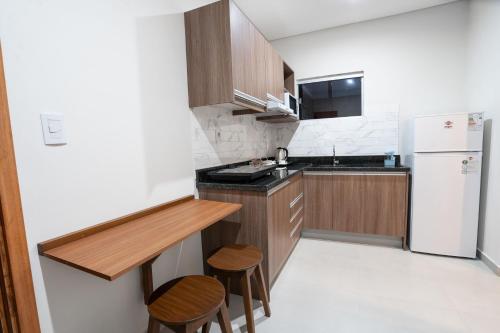 a kitchen with a white refrigerator and wooden cabinets at VIVARIUM APART HOTEL in Asuncion