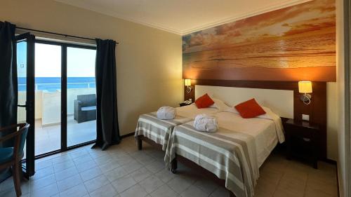 een slaapkamer met een bed en uitzicht op de oceaan bij Hotel Avenida Praia in Portimão