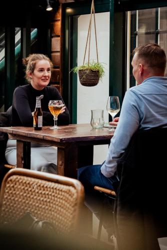 a man and a woman sitting at a table with wine glasses at Long John's Pub & Hotel in Amersfoort