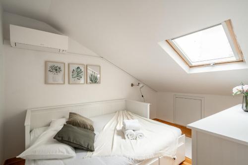 a bedroom with a white bed in a attic at Akicity Anjos Splendid in Lisbon