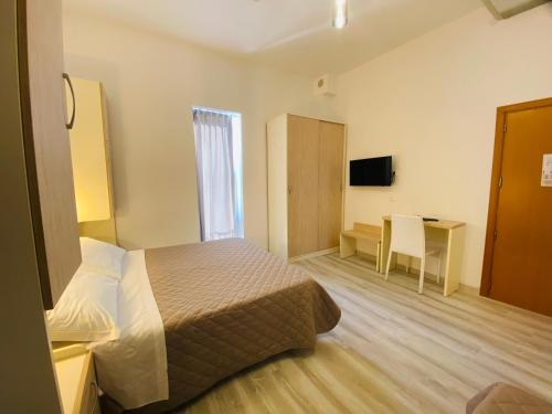 a hotel room with a bed and a desk and a television at Hotel Butterfly in Rimini