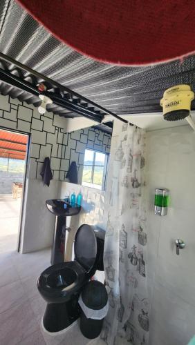 a bathroom with a black toilet and a sink at Carpe Diem in Guatavita