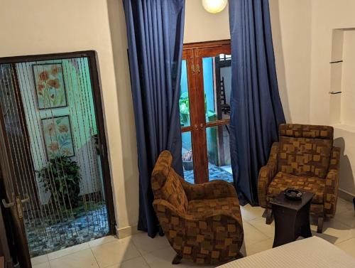 uma sala de estar com duas cadeiras e uma janela em The Traditional Villa by ceyio em Matara