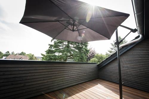 een zwarte parasol op een balkon met zon bij Heaven House Penthousewohnung Siebter Himmel in Timmendorfer Strand
