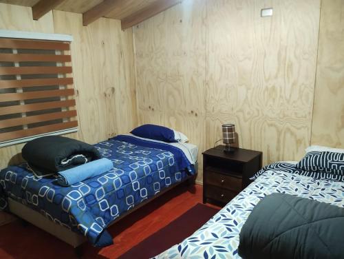 um quarto com duas camas e uma mesa de cabeceira em Residencial 4 estaciones em Futaleufú