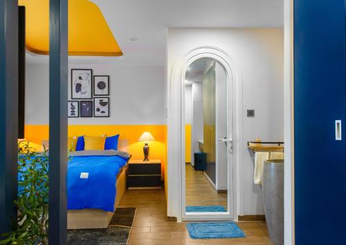 um quarto com uma cama azul e uma parede amarela em Pavillon Garden Hotel & Spa Nha Trang em Nha Trang