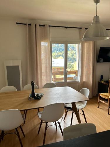 une table de salle à manger avec des chaises et une grande fenêtre dans l'établissement Confortable appartement rénové centre Villard de Lans, à Villard-de-Lans