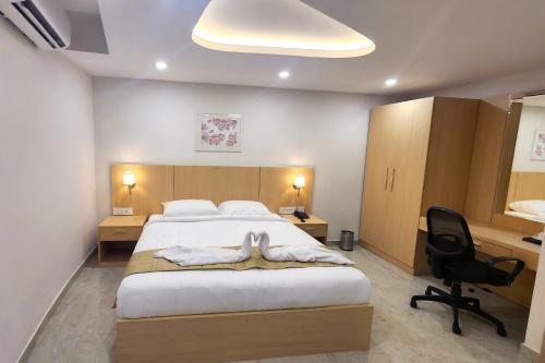a bedroom with a bed and a desk and a chair at Sauparnika Regency in Trichūr