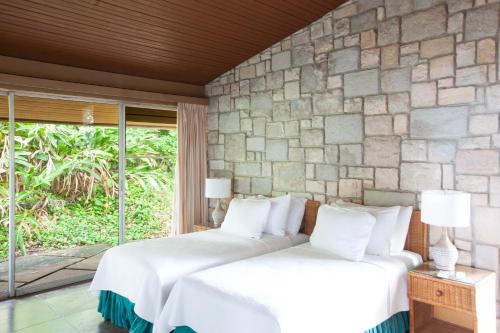 two beds in a room with a stone wall at Frenchman's Cove Resort in Port Antonio