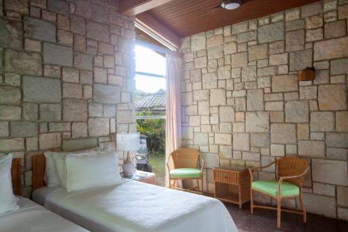a bedroom with two beds and a stone wall at Frenchman's Cove Resort in Port Antonio