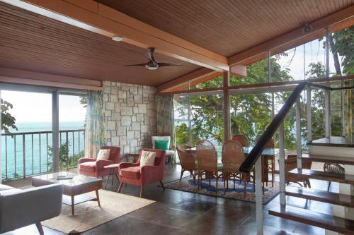 a living room with a table and chairs and windows at Frenchman's Cove Resort in Port Antonio