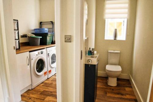 a bathroom with a toilet and a washer and dryer at 3BD Gem in the Heart of Barnetby Le Wold in Barnetby le Wold