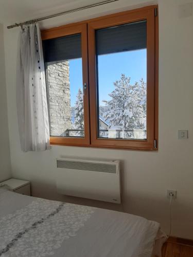 a bedroom with a window with a snow covered tree at Apartman TIO Binis in Zlatibor