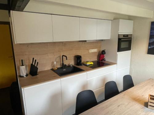 a kitchen with white cabinets and a sink and a table at Cottage 213 in Sunparks Oostduinkerke with free parking and garden in Koksijde