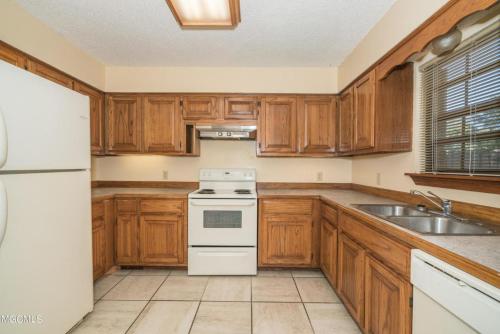 a kitchen with wooden cabinets and a white stove top oven at Oakhaven in Long Beach