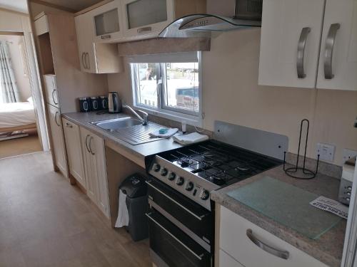 a small kitchen with a stove and a sink at Luxurious Wheelchair-Friendly holiday home at Kent Coast Holiday Park in Allhallows
