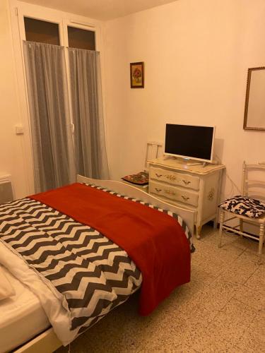 a bedroom with a bed and a dresser with a television at 200m de la plage ,3mn du port à 50m du centre ville in Carry-le-Rouet