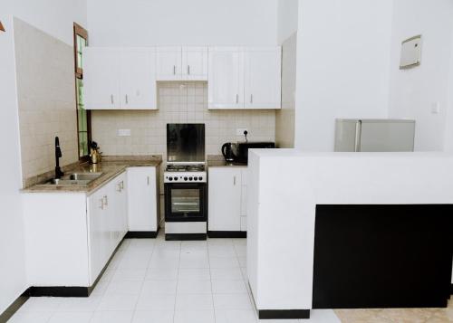 a kitchen with white cabinets and a stove top oven at LM Apartments in Dar es Salaam