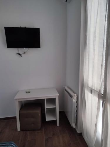 una piccola scrivania bianca con TV e tavolo di ALO ALO ALBERGO a Casteggio