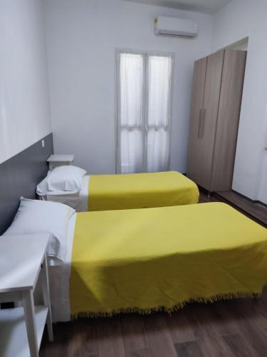 2 Betten mit gelber Bettwäsche in einem Zimmer in der Unterkunft ALO ALO ALBERGO in Casteggio