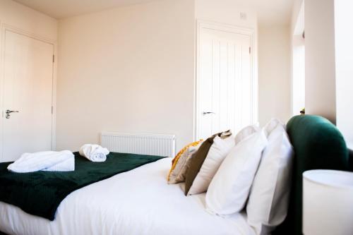 a bedroom with a white bed with white pillows at Cotswolds-Stroud-Comfy 4 bed house-Sleeps 10-Free Parking-Wifi in Ebley