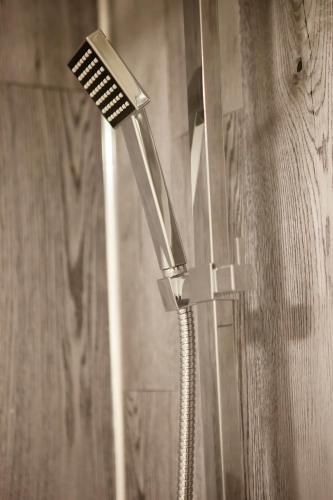 a shower with a shower head on a wall at Cotswolds-Stroud-Comfy 4 bed house-Sleeps 10-Free Parking-Wifi in Ebley