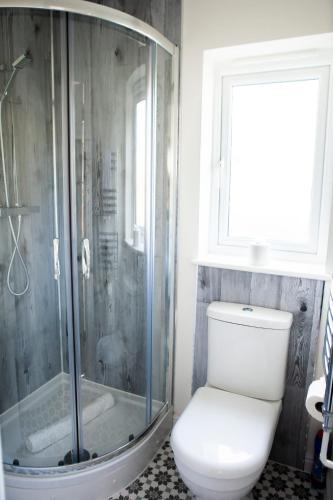 a bathroom with a toilet and a glass shower at Cotswolds-Stroud-Comfy 4 bed house-Sleeps 10-Free Parking-Wifi in Ebley