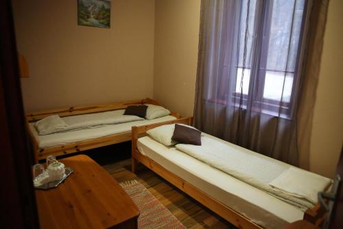 a room with two beds and a table and a window at Déjá Vu Szállás & Rendezvény Zirc in Zirc