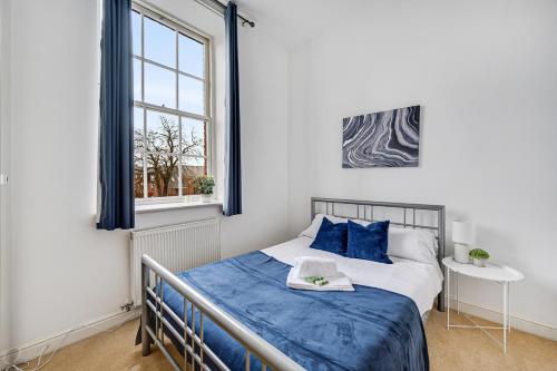 ein Schlafzimmer mit einem Bett mit blauen Kissen und einem Fenster in der Unterkunft Pass the Keys Luxury 2 Apt in West Didsbury in Manchester