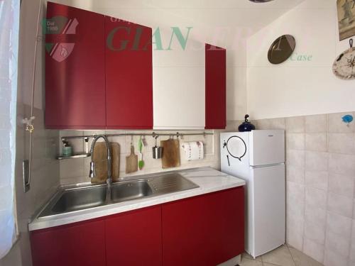 eine Küche mit roten Schränken, einer Spüle und einem Kühlschrank in der Unterkunft 7 posti letto con accesso diretto al mare - PAPI in San Vincenzo