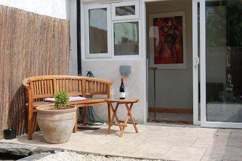 a wooden bench and a bottle of wine on a patio at Y Bwthyn Bach Cute Stone Cottage in Tywyn in Tywyn