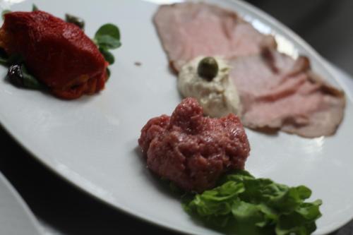 a plate of food with meat and greens on it at Locanda del Boscogrande in Montegrosso dʼAsti
