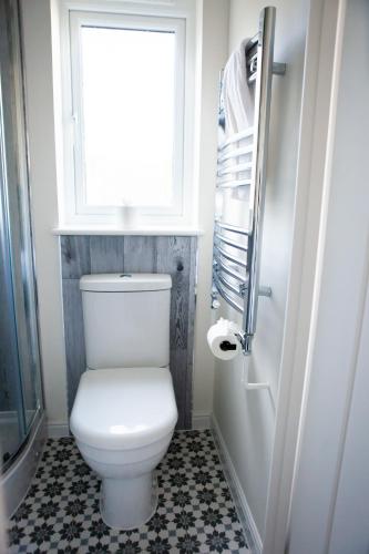 a bathroom with a white toilet and a window at Cotswolds-Stroud-Comfy 4 bed house-Sleeps 10-Free Parking-Wifi in Ebley