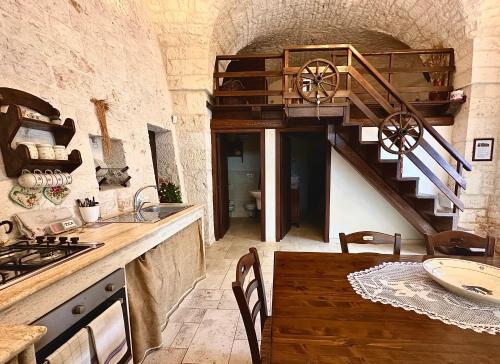 a kitchen with a wooden spiral staircase and a table at La Pergola in Locorotondo