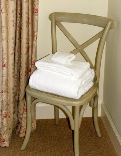 a wooden chair with towels on it in front of a curtain at Beautiful spacious old schoolhouse with stunning sea views and beach nearby in Port Bannatyne
