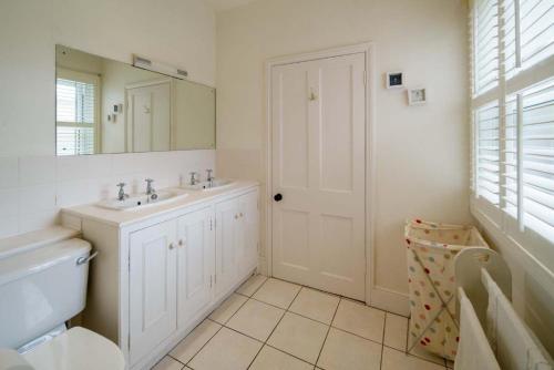 uma casa de banho branca com um lavatório e um espelho em Flat 1, Baymount em Seaview