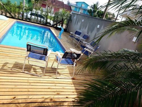 un grupo de sillas sentadas en una terraza cerca de una piscina en Casa com piscina / Na quadra do mar Torres-RS en Torres