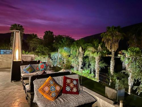 a patio with a couch and palm trees at night at Desert Nights Hostel in Ica