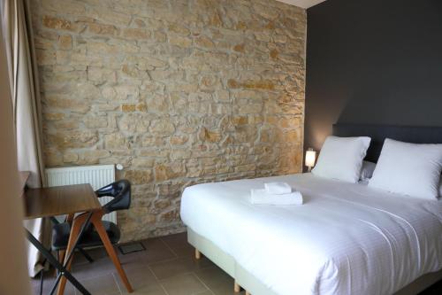 a bedroom with a bed and a stone wall at Séquoias Golf & Ressort in Ruy
