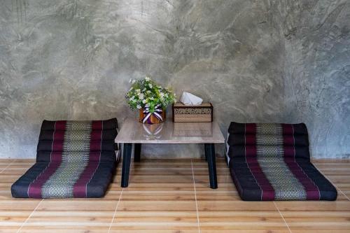 a table with a vase of flowers and two chairs at Smilingface guesthouse in Sukhothai