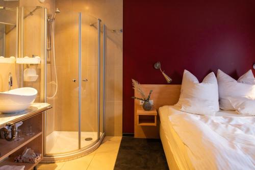 uma casa de banho com um chuveiro, uma cama e um lavatório. em Mein SchlossHotel em Heusenstamm