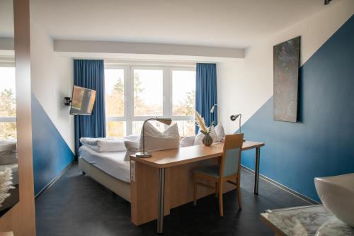 1 dormitorio con escritorio, 1 cama y ventana en Mein SchlossHotel, en Heusenstamm