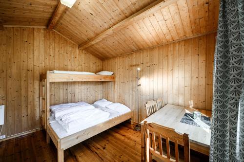 um quarto em madeira com um beliche e uma mesa em Korsbakken Camping em Isfjorden