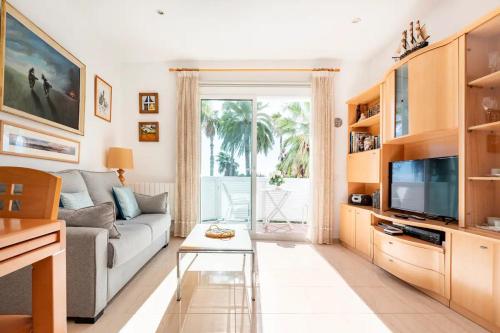 a living room with a couch and a tv at Sitges Seafront Ribera Apartment in Sitges